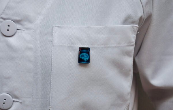 MedArtz Brain Pin on a white coat, front close view.