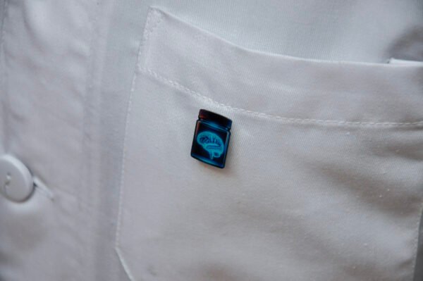 MedArtz Brain Pin on a white coat, front close view.